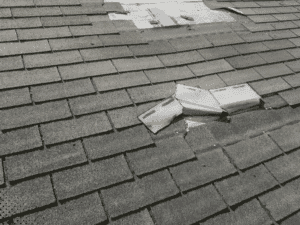lose-up of cracked and displaced asphalt shingles caused by hail or high wind damage