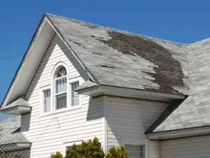 Residential roof with missing and deteriorated shingles from storm-related damage