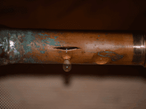 Close-up of corroded copper plumbing pipe with active leak identified during home inspection in Dallas TX