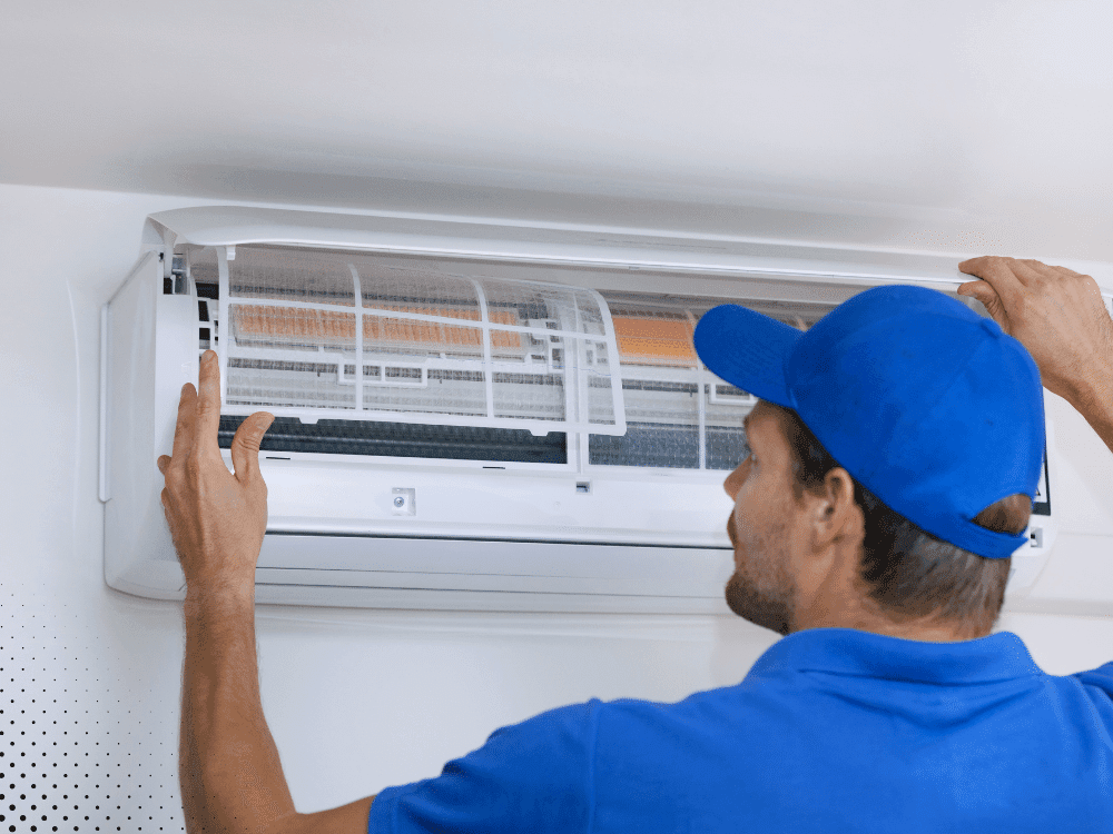 technician inspecting and cleaning indoor AC air filter during home inspection